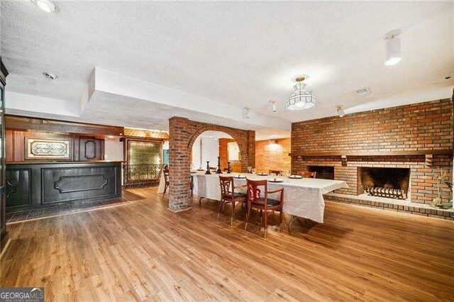 kitchen with a brick fireplace, light hardwood / wood-style floors, and a textured ceiling