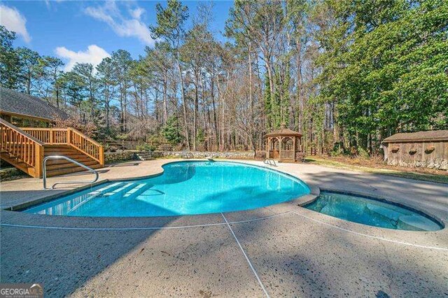 view of pool with a gazebo and an in ground hot tub