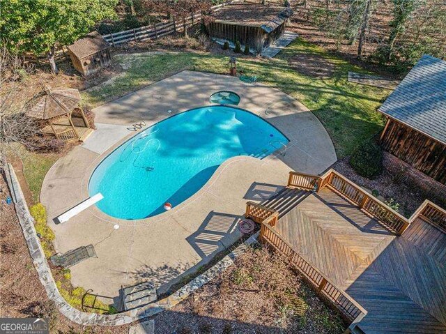 view of swimming pool featuring a wooden deck, a diving board, and a shed