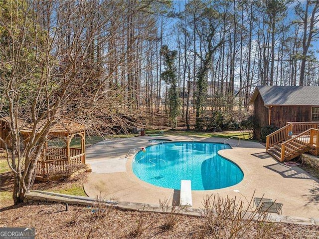 view of swimming pool featuring a patio, a gazebo, a diving board, and a deck