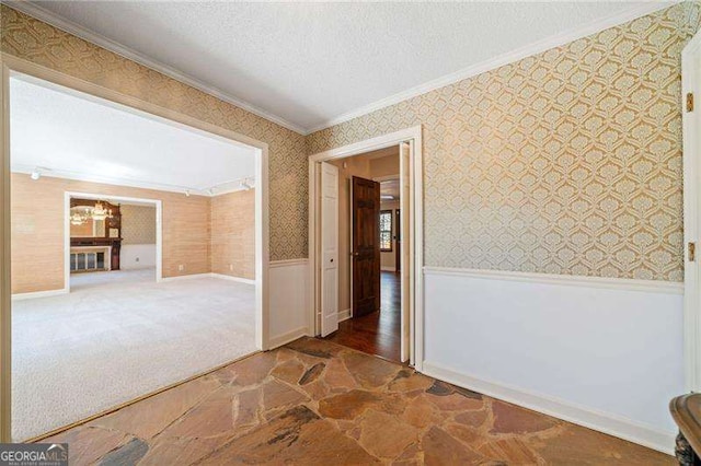 empty room with ornamental molding, a textured ceiling, and dark colored carpet