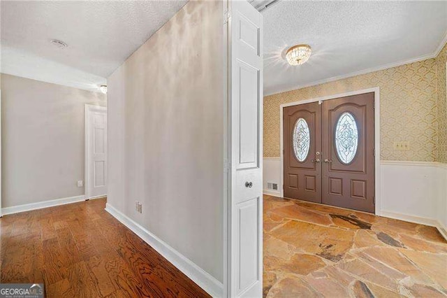 foyer featuring ornamental molding, wood-type flooring, and a textured ceiling