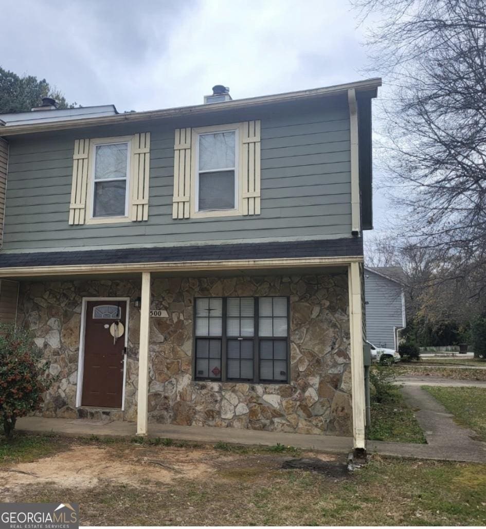 view of front of house with stone siding and a chimney