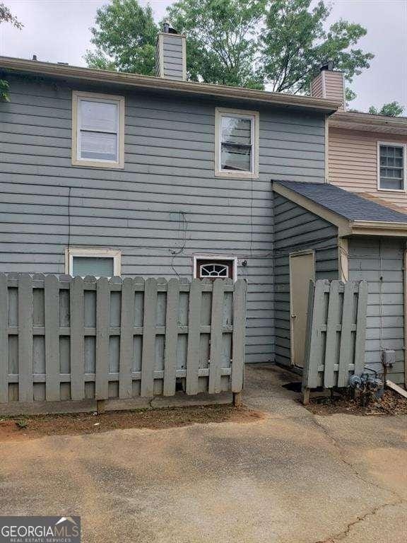 back of property with a chimney and fence