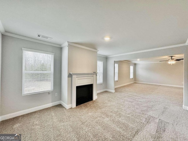 unfurnished living room featuring ornamental molding, plenty of natural light, and light carpet