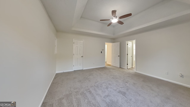 carpeted empty room with ceiling fan and a tray ceiling