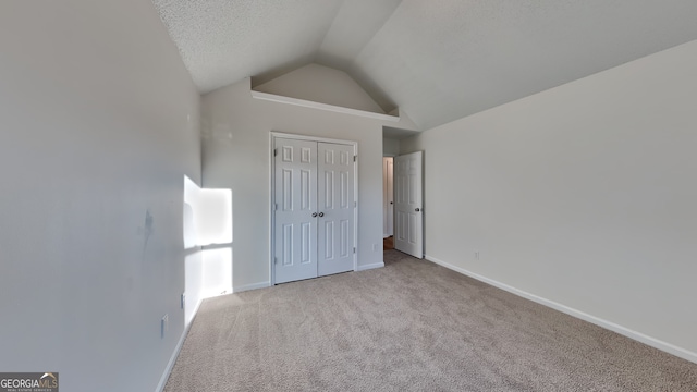 unfurnished bedroom with vaulted ceiling, light colored carpet, a closet, and a textured ceiling