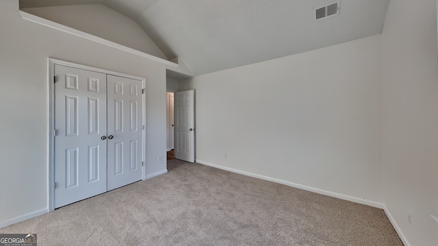 unfurnished bedroom with a closet, lofted ceiling, and light carpet