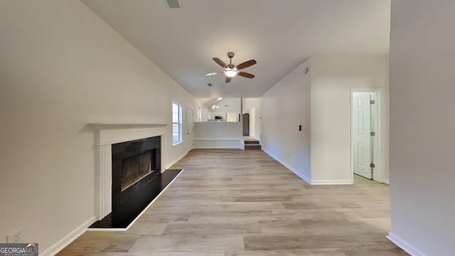 unfurnished living room featuring ceiling fan, lofted ceiling, a high end fireplace, and light wood-type flooring