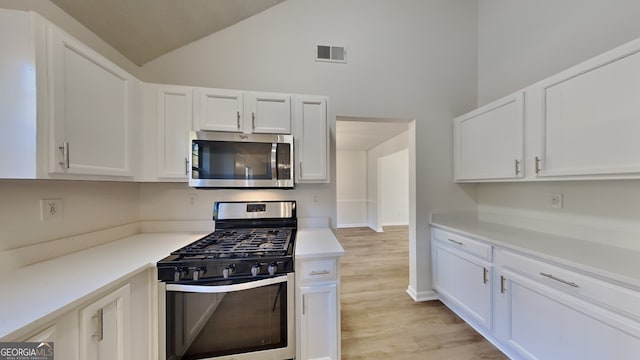 kitchen with high vaulted ceiling, stainless steel appliances, light hardwood / wood-style floors, and white cabinets