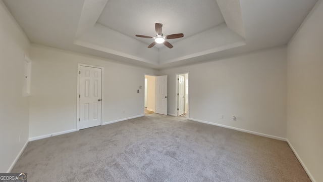 carpeted spare room with a tray ceiling and ceiling fan