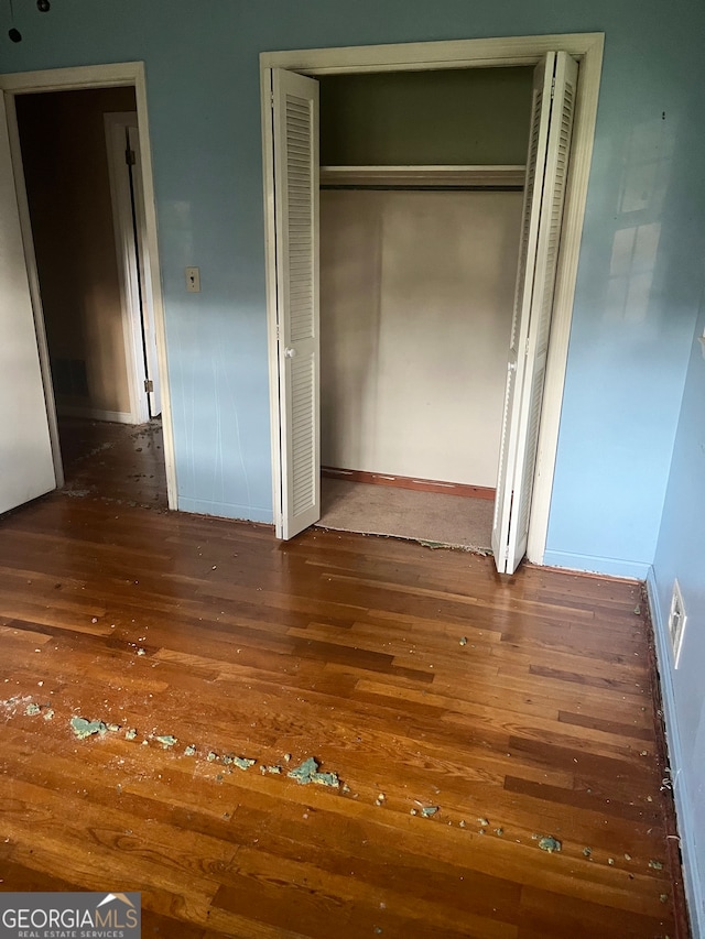 unfurnished bedroom featuring dark hardwood / wood-style flooring and a closet