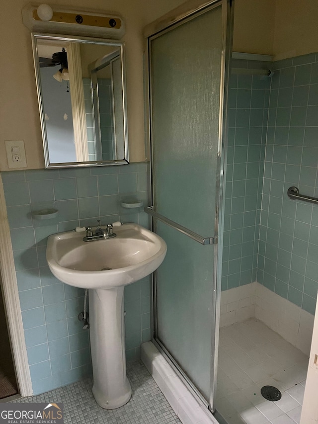 bathroom with tile walls, an enclosed shower, and tile patterned floors