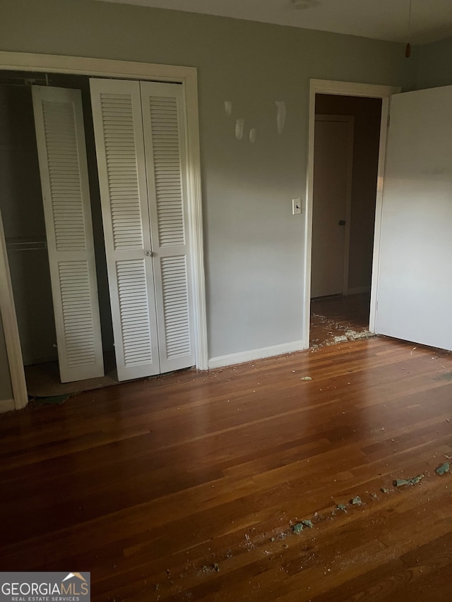 unfurnished bedroom featuring dark hardwood / wood-style flooring and a closet