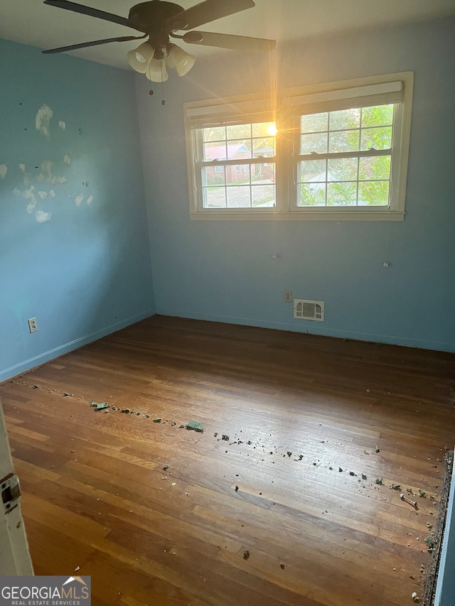 empty room featuring ceiling fan, hardwood / wood-style floors, and a wealth of natural light