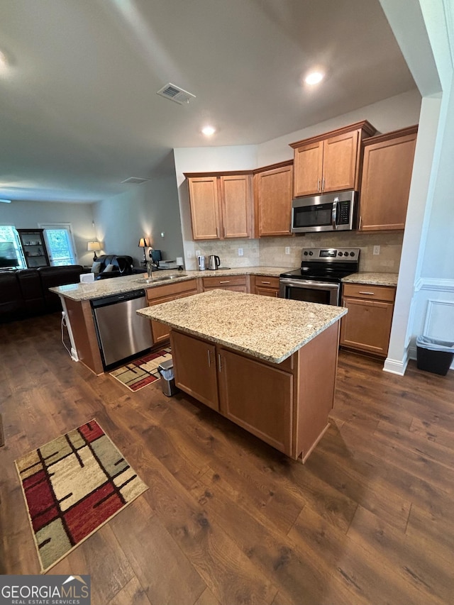 kitchen with a breakfast bar area, appliances with stainless steel finishes, dark hardwood / wood-style floors, kitchen peninsula, and light stone countertops