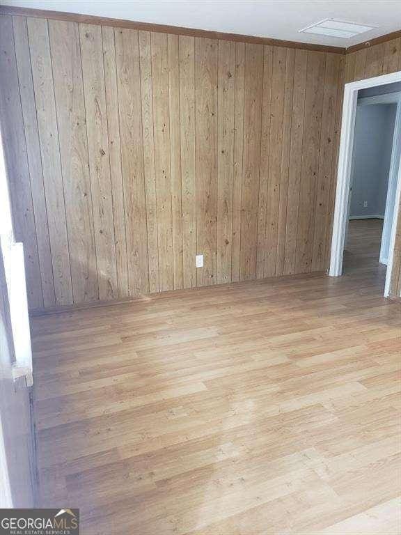 empty room featuring wood walls and light hardwood / wood-style flooring