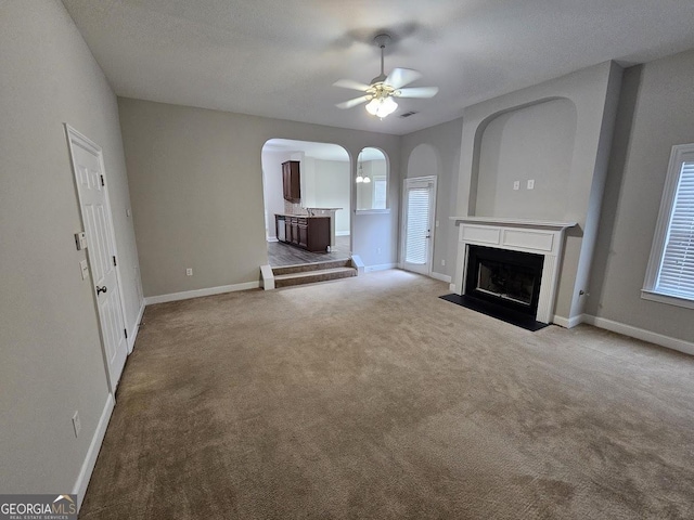 unfurnished living room featuring ceiling fan, light colored carpet, and a healthy amount of sunlight