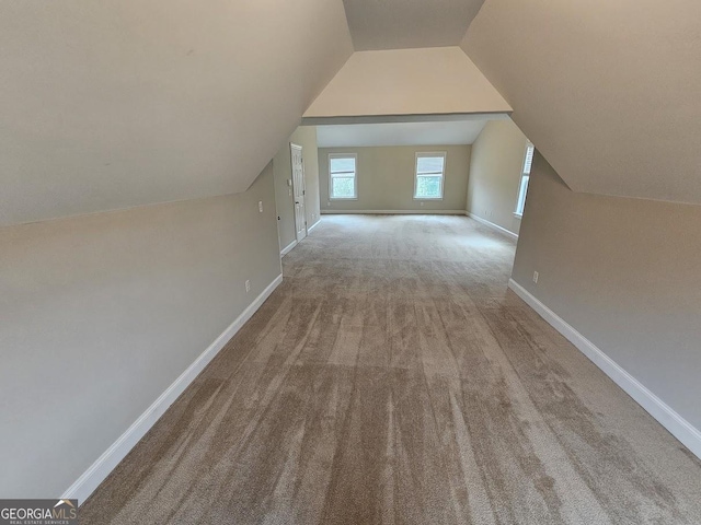 bonus room with lofted ceiling and light colored carpet