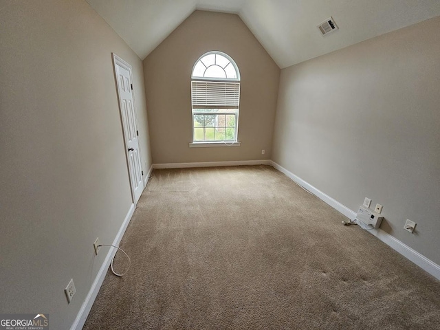 empty room featuring vaulted ceiling and light colored carpet