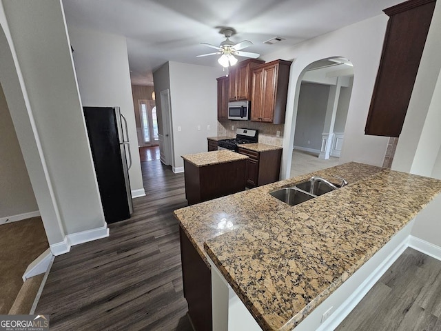 kitchen featuring dark hardwood / wood-style floors, sink, light stone counters, kitchen peninsula, and stainless steel appliances