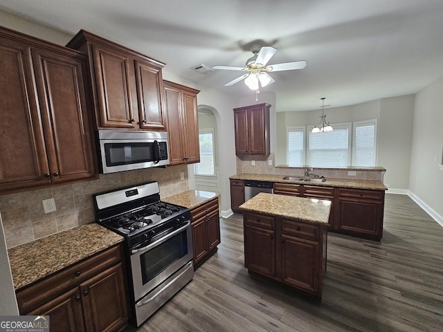 kitchen with a kitchen island, appliances with stainless steel finishes, dark hardwood / wood-style floors, decorative light fixtures, and sink