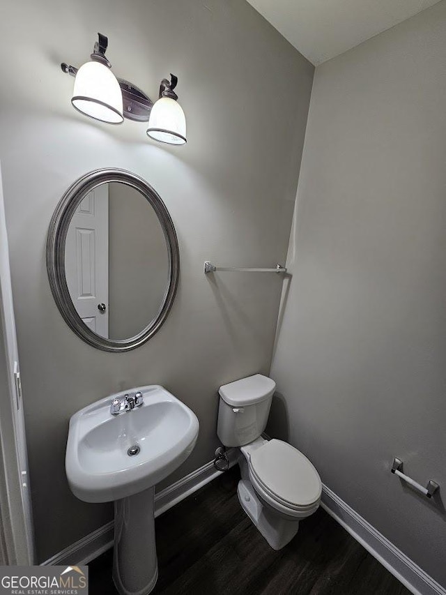 bathroom with wood-type flooring, toilet, and sink