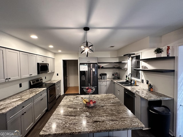 kitchen with pendant lighting, sink, a kitchen island, and black appliances