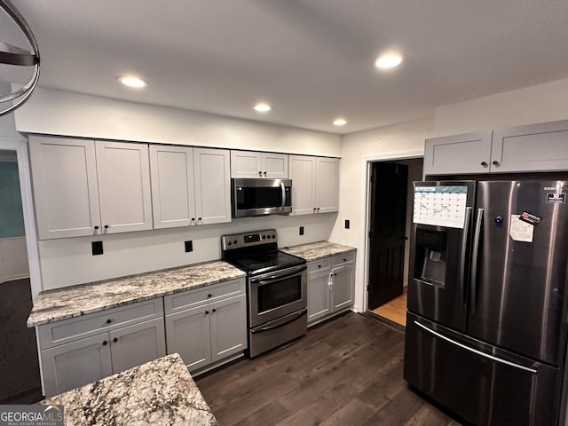 kitchen with gray cabinetry, light stone countertops, stainless steel appliances, and dark hardwood / wood-style floors