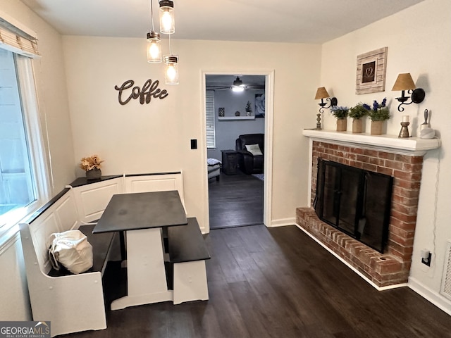 dining room with dark hardwood / wood-style flooring and a brick fireplace