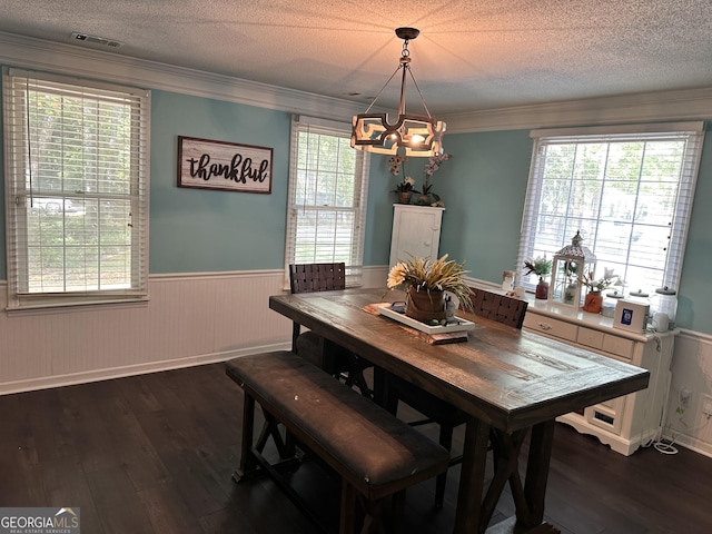 dining space featuring dark wood-type flooring, ornamental molding, a chandelier, and a textured ceiling