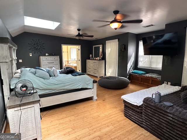 bedroom with vaulted ceiling with skylight, ceiling fan, and light hardwood / wood-style flooring