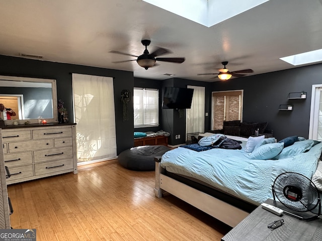 bedroom featuring ceiling fan, light hardwood / wood-style floors, and a skylight