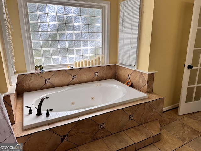 bathroom with a relaxing tiled tub and plenty of natural light