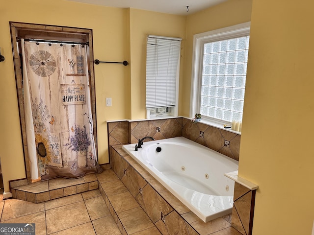 bathroom with tile patterned flooring, tiled tub, and plenty of natural light