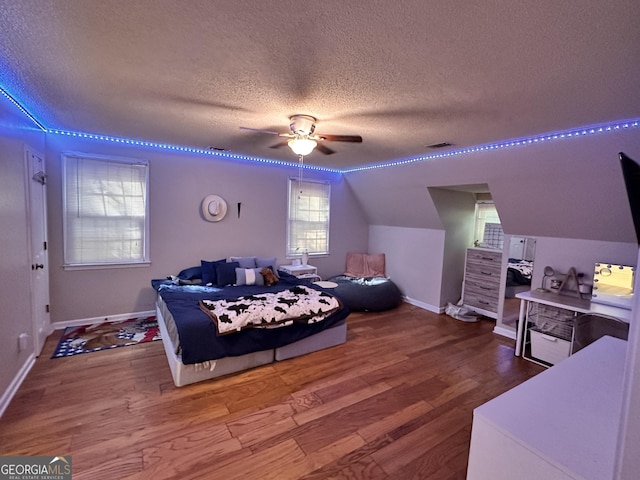 bedroom with ceiling fan, lofted ceiling, hardwood / wood-style floors, and a textured ceiling