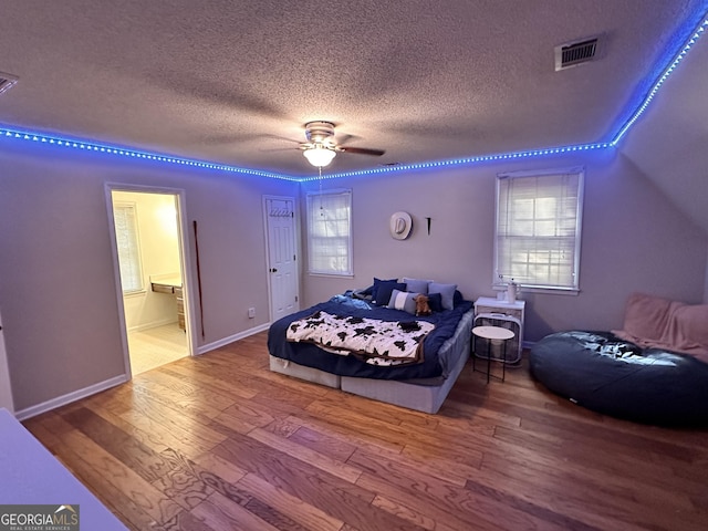 bedroom with hardwood / wood-style flooring, ceiling fan, connected bathroom, and a textured ceiling