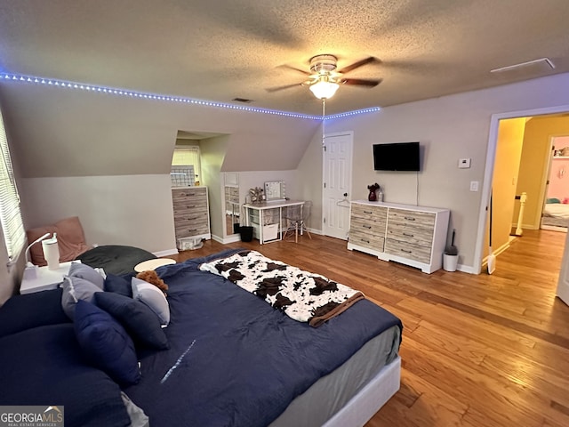 bedroom with lofted ceiling, ceiling fan, hardwood / wood-style flooring, and a textured ceiling