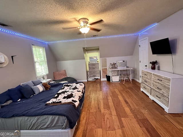 bedroom with lofted ceiling, hardwood / wood-style floors, a textured ceiling, and ceiling fan