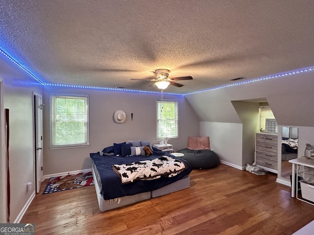 bedroom with wood-type flooring, a textured ceiling, and vaulted ceiling