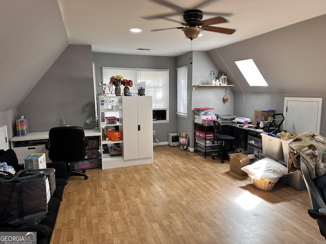 office space with vaulted ceiling with skylight, ceiling fan, and light hardwood / wood-style flooring