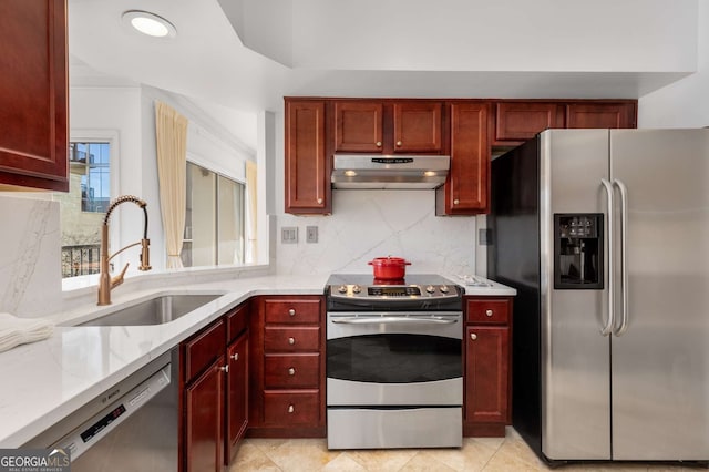 kitchen featuring light stone countertops, appliances with stainless steel finishes, sink, and backsplash