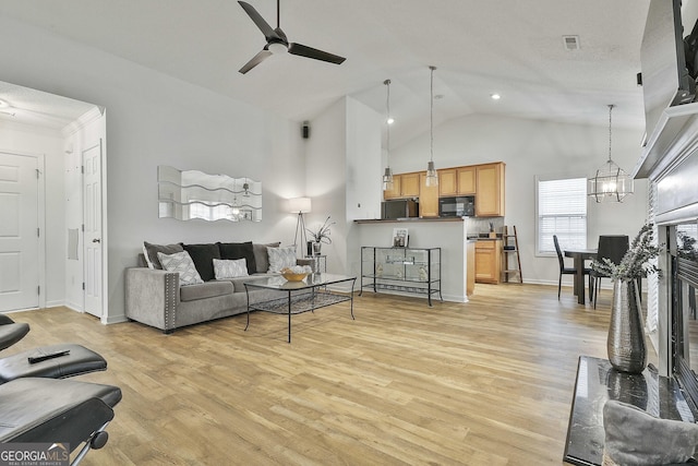 living room featuring ceiling fan with notable chandelier, high vaulted ceiling, and light wood-type flooring