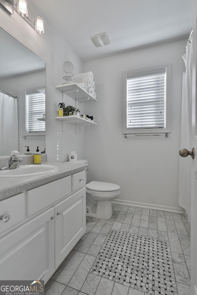 bathroom featuring vanity, plenty of natural light, and toilet