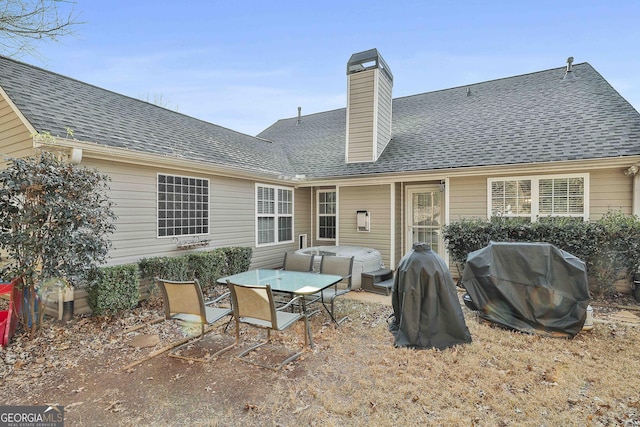 back of property with a hot tub and a patio