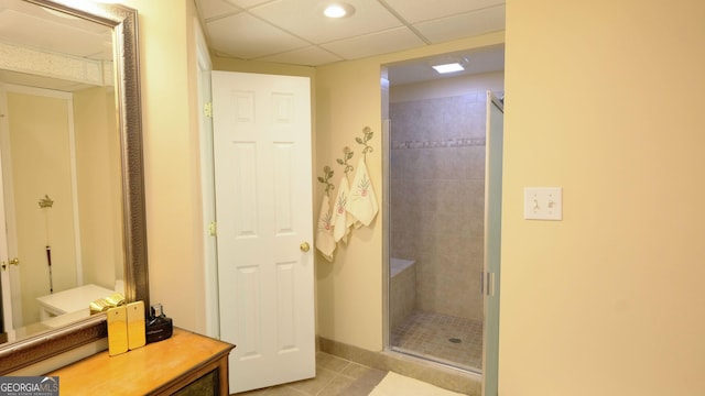 bathroom featuring tile patterned flooring, a shower with door, and a drop ceiling