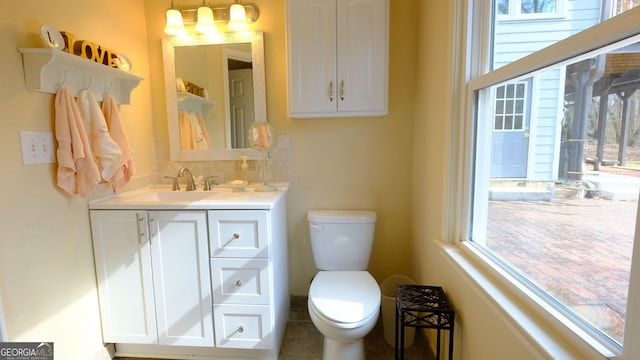 bathroom with vanity, toilet, an inviting chandelier, and decorative backsplash