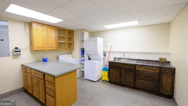 clothes washing area with stacked washer and dryer, sink, electric panel, and cabinets