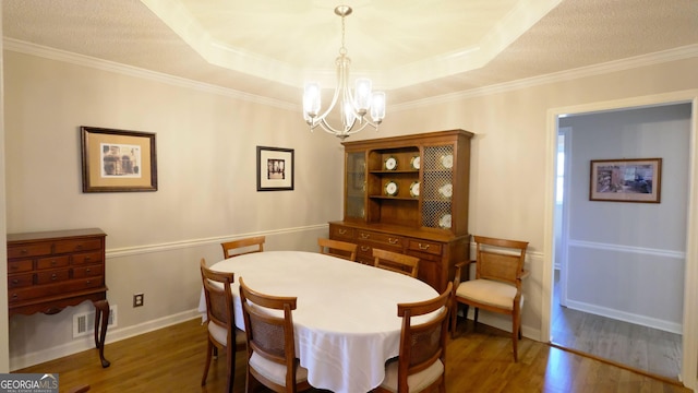 dining room with a raised ceiling, a chandelier, and dark hardwood / wood-style flooring