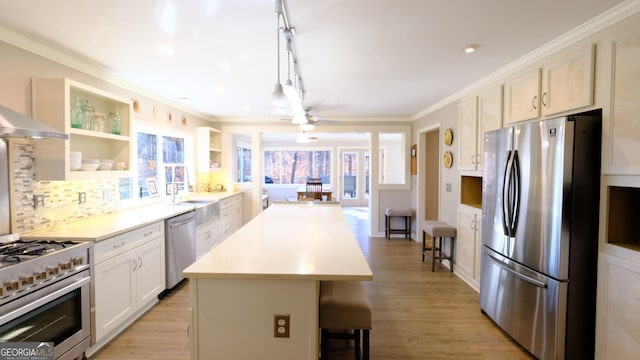 kitchen with crown molding, white cabinetry, stainless steel appliances, a center island, and decorative light fixtures